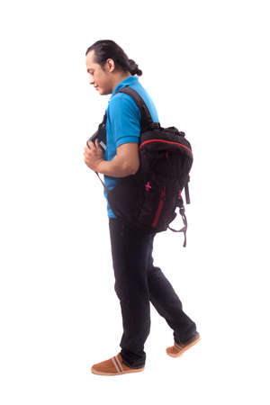 Portrait of a cute young Asian male student with long hair,walking forward while holding laptop, side view isolated on whiteの写真素材