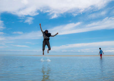 Muslim family having fun on beach and blue ocean landscape, halal tourism destination conceptの写真素材