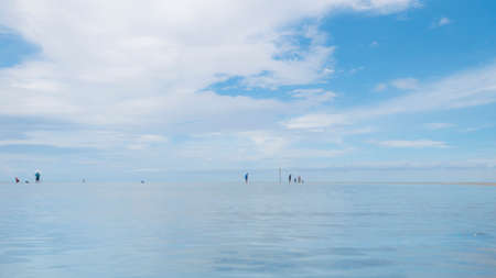 Beach and blue ocean landscape with white clouds on blue sky, with people in distanceの写真素材