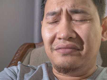 Photo image of funny Asian man crying close his eyes, sad depression frustration hopeless expression