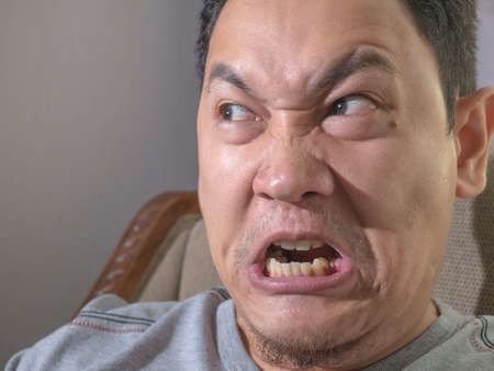 Angry young Asian man looks really mad of something bad. Close up head and shouldersの写真素材