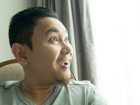 Funny young Asian man wearing casual grey shirt thinking, looking to the side. Close up body portraitの写真素材