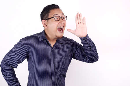 Portrait of young Asian businessman speaking out loud, against white background with copy space