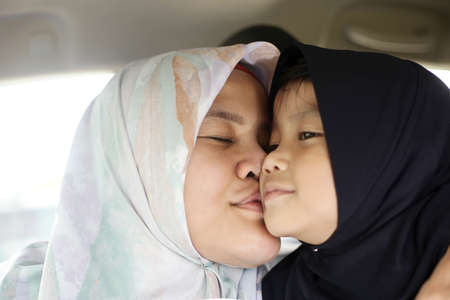 Portrait of happy muslim mom and daughter, Asian mother kiss her baby girl in carの写真素材