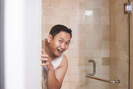 Portrait of funny Asian man smiling happily in bathroomの写真素材