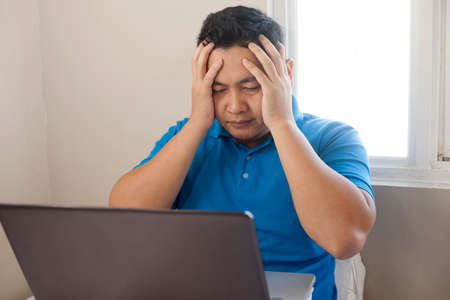Portrait of young Asian man looked upset disappointed stress and headache to see bad things on internet, bad business conceptの写真素材