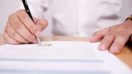 Close up image of businessman signing contract or student having exam test, selective focus