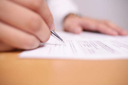 Close up image of businessman signing contract or student having exam test, selective focusの写真素材