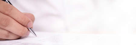 Close up image of businessman signing contract or student having exam test, wide view with selective...