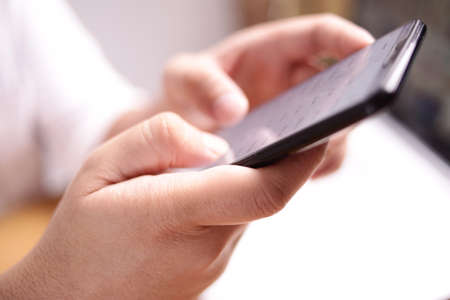 Close up image of businessman holding and using smart phone with selective focus