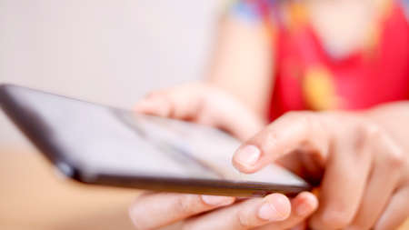 Close up image of woman using smart phone, focus on fingers holding phone with selective focus