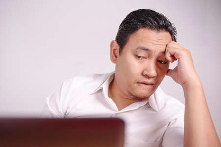 Portrait of Asian man Looked tired upset, depresssed and stressed looking at laptop, sleepy tired stress gesture, bad business pressure, work addict conceptの写真素材