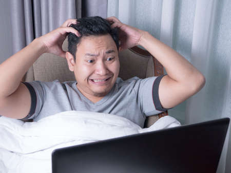 Portrait of young Asian man looked upset disappointed stress and headache to see bad things on internet, bad business conceptの写真素材
