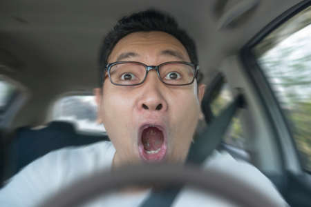 Portrait of male Asian driver shocked and panic about to have crash accident, close up with open mouthの写真素材