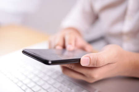 Close up image of businessman holding and using smart phone with selective focus