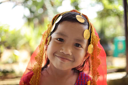 Close up portrait of cute beautiful little Asian Indian girl with head scarf smilingの写真素材