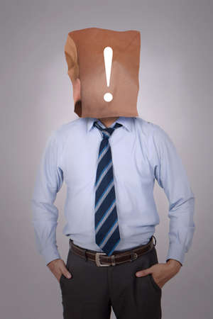 Portrait of businessman covering his face with paper mask with punctutation mark symbol on it. copy space mock up for anonymouse personの写真素材