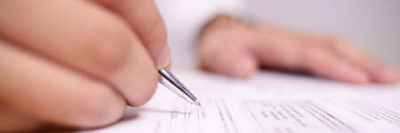 Close up image of businessman signing contract or student having exam test, wide view with selective...