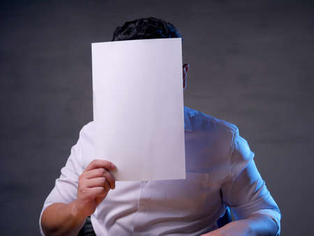Portrait of businessman covering his face with blank empty paper. copy space mock up for anonymouse personの写真素材