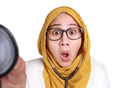 Female Asian muslim doctor holding a stethoscope, seriously  listening gesture, doctor checking with stethoscope, shocked gestureの写真素材