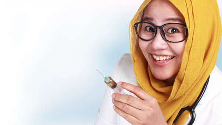 Portrait of female Asian muslim doctor smiling when holding injection syringe