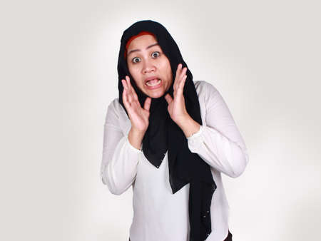 Portrait of cute young Asian muslim lady wearing hijab shows surprised or shocked expression with open mouth, close up facial expressionの写真素材