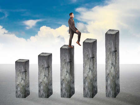 Businessman walking up on business growth diagram made of stone, success chart graphic conceptの写真素材