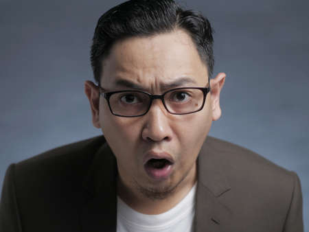 Asian businessman wearing suit shocked surprised expression with open mouth. Close up body portraitの写真素材