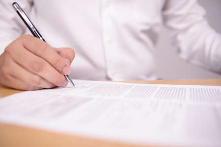 Close up image of businessman signing contract or student having exam test, selective focus