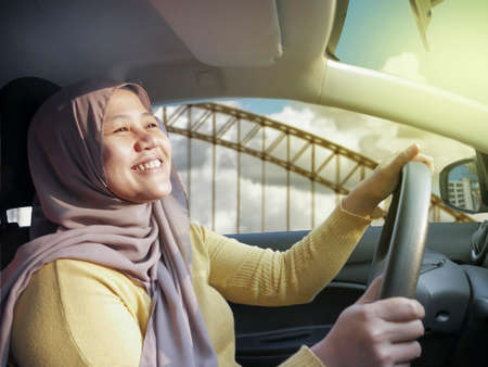 Portrait of young Asian muslim woman smiling and driving a car, good looking entrepreneur, car...