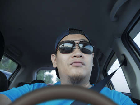 Portrait of young Asian male driver smiling happily, driver taking selfie photograph, friendly ride...