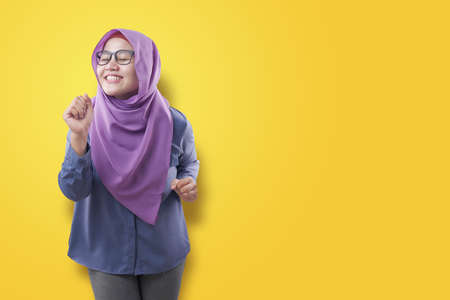 Portrait of a funny young Asian muslim woman wearing hijab dancing happily joyful expressing celebrating good news victory winning success gesture, smiling positive excited emotion isolated on whiteの写真素材