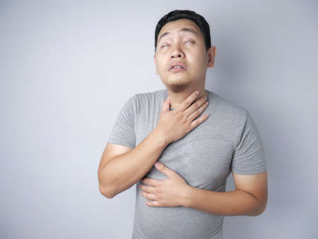 Funny young Asian man wearing suffer from throat pain. Close up body portraitの写真素材