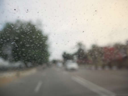 Close up image with selective focus of rain drops on dirty car front window