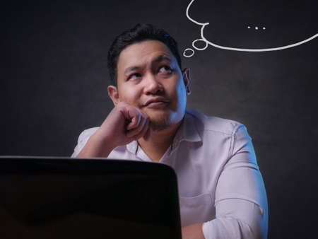 Young Asian man smiling thinking expression looking for idea, solution for a problem. Close up body portraitの写真素材