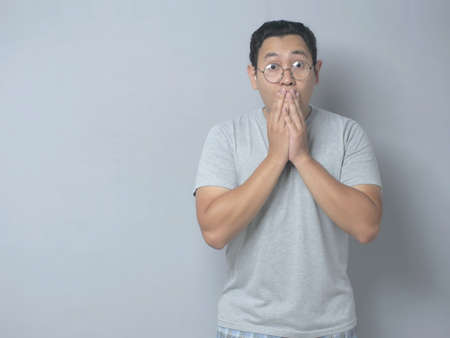 Close up portrait of attractive Asian young man closing his mouth with fingers. Worried gesture, can't say anything. Shocked surprised to hear bad news or gossip, looking at cameraの写真素材