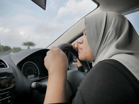 Portrait o Asian muslim lady slept in her car, tired in the trip, taking nap by the side of the road