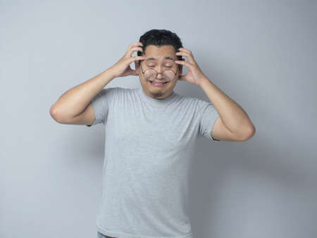 Young Asian man looked frustrated having a headache, stress expression. Close up portrait against grey backgroundの写真素材