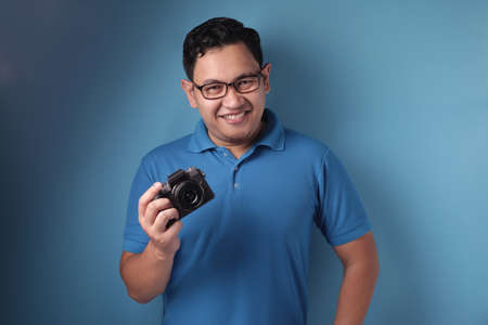 Portrait of funny young Asian man taking picture, shoot with his camera, casual photographer in...