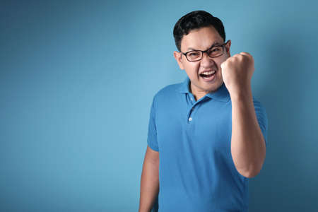 Portrait of a funny young Asian man dancing happily joyful expressing celebrating good news victory winning success gesture, smiling positive excited emotionの写真素材