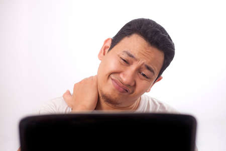 Portrait of young Asian man looked tired and suffer from stiffed neck pain after working on laptop...