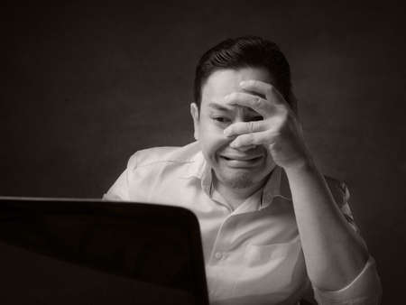 Portrait of young Asian man looked afraid terrified worried when looking at laptop, gasp gesture...