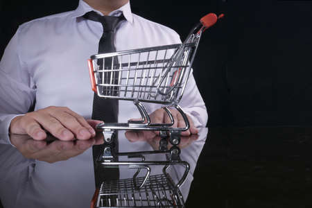 Close up anonymous businessman with mini trolley shopping cart, e-commerce conceptの写真素材