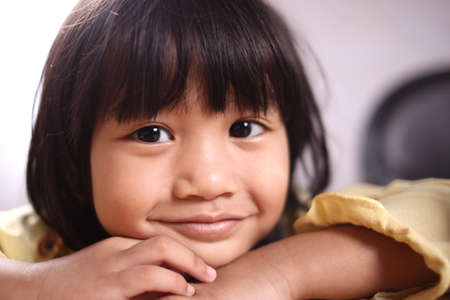 Portrait of little Asian girl looking at camera and smilingの写真素材