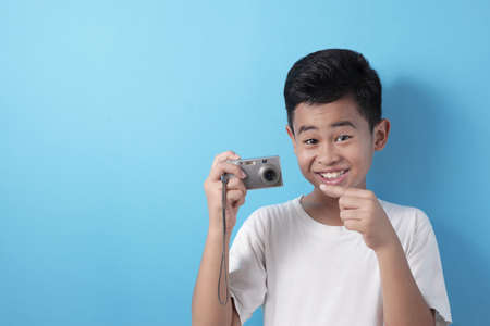 Happy Asian boy doing photography leisure activity, kid as photographer taking picture with his...