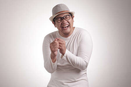 Portrait of funny young Asian man laughing hard with big open mouth, over white background