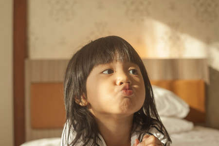 Portrait of cute adorable little Asian baby girl shows curiosity expression, looking to the sideの写真素材