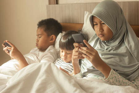 Little kids sister and brother siblings plays on gadget smart phone, phone addiction on children conceptの写真素材