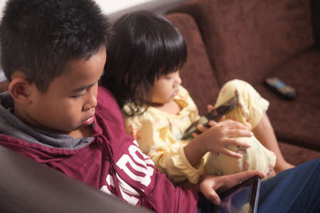 Little kids sister and brother siblings plays on gadget smart phone, phone addiction on children...