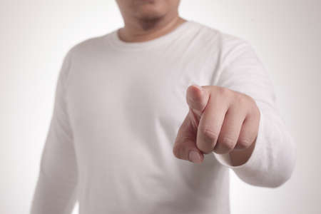 Portrait of young Asian man pointing forward, looking at camera. Choosing someone concept with selective focusの写真素材